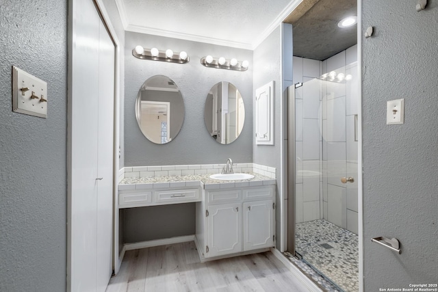 bathroom featuring hardwood / wood-style floors, vanity, ornamental molding, an enclosed shower, and a textured ceiling