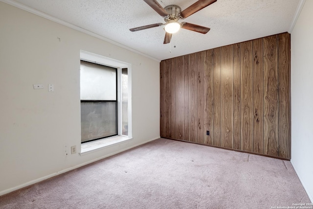 carpeted empty room featuring crown molding, a textured ceiling, and wooden walls