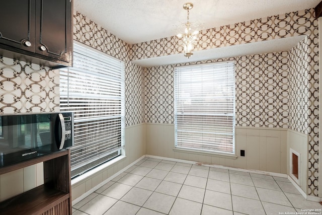 dining space featuring light tile patterned flooring, a textured ceiling, and a wealth of natural light