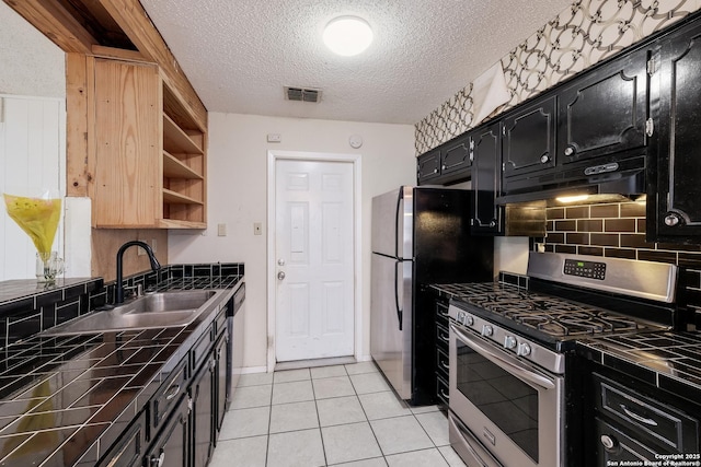 kitchen with light tile patterned flooring, appliances with stainless steel finishes, tile countertops, sink, and backsplash