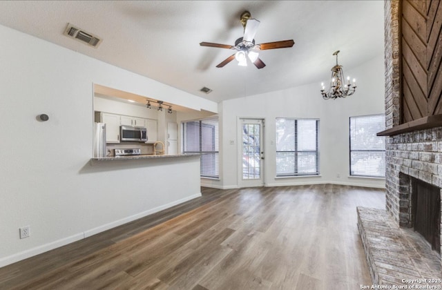 unfurnished living room featuring dark wood-type flooring, sink, vaulted ceiling, ceiling fan, and a fireplace