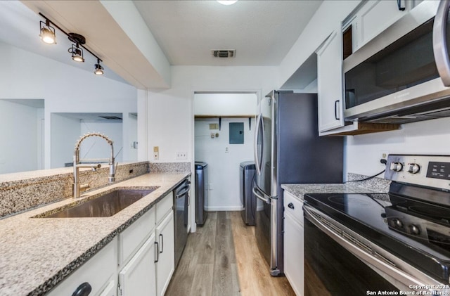 kitchen featuring sink, light wood-type flooring, appliances with stainless steel finishes, light stone countertops, and white cabinets