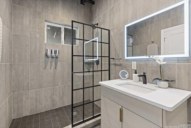 bathroom featuring vanity, a tile shower, backsplash, and tile walls