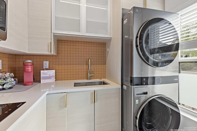 laundry area featuring stacked washing maching and dryer and sink