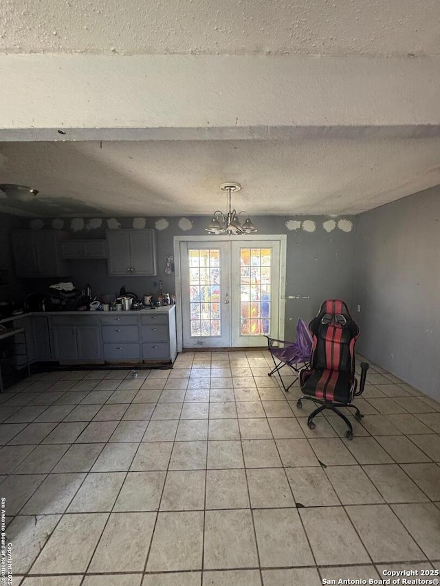 unfurnished dining area featuring light tile patterned floors, a chandelier, french doors, and a textured ceiling