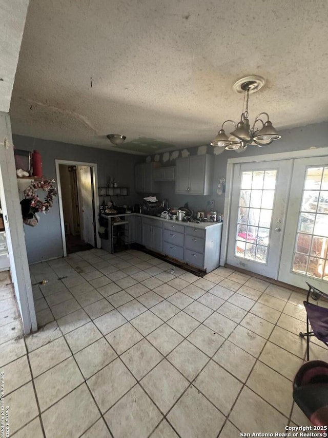 kitchen with light tile patterned flooring, gray cabinetry, an inviting chandelier, range, and a textured ceiling