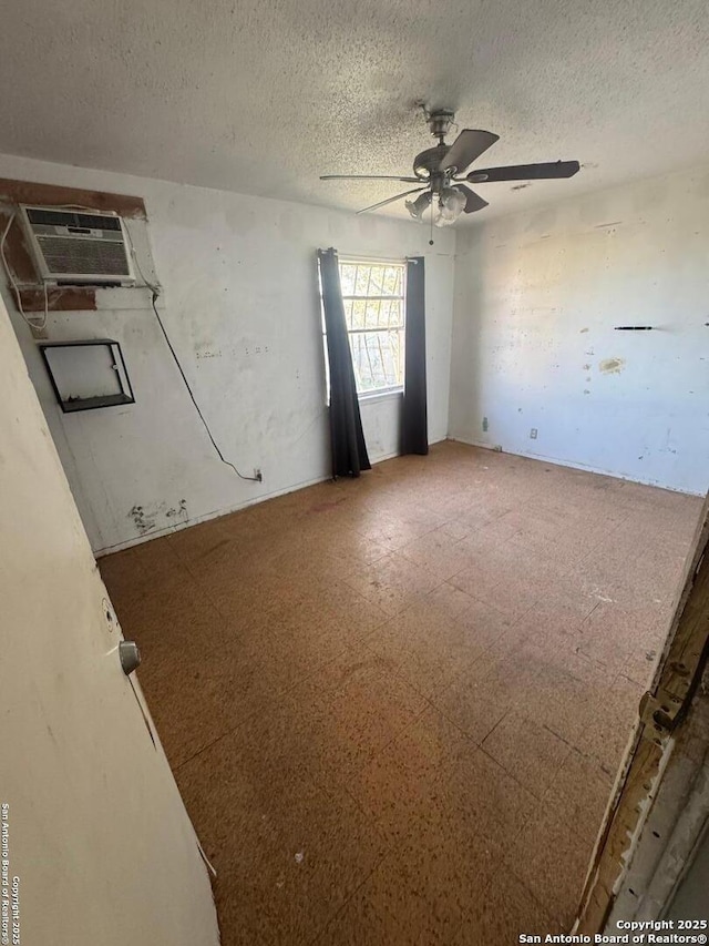 empty room with ceiling fan, a wall mounted air conditioner, and a textured ceiling