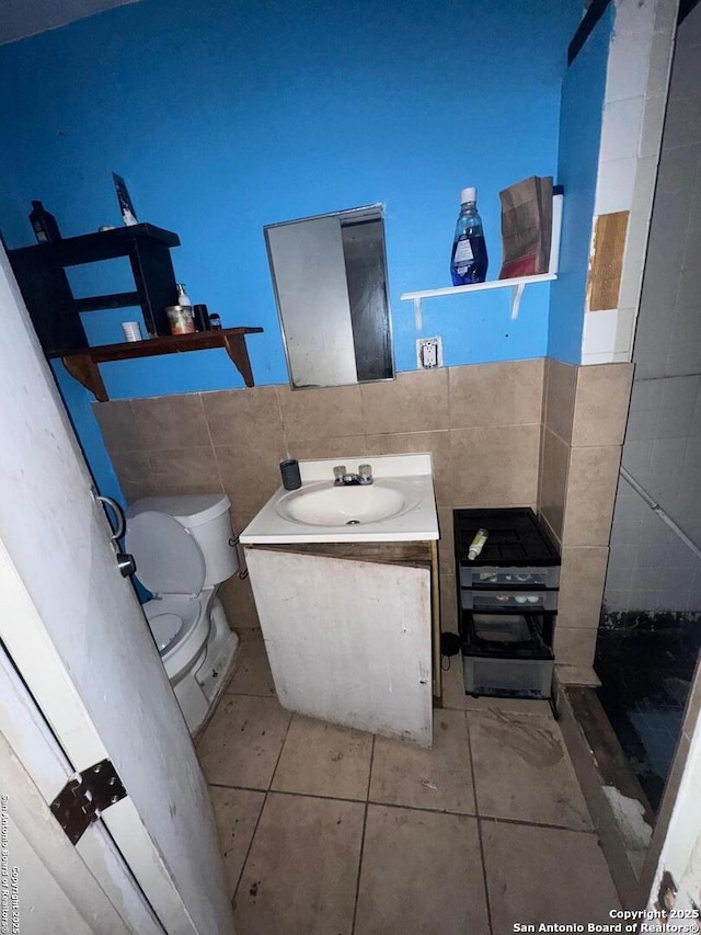 bathroom with tile patterned floors, toilet, tile walls, and vanity