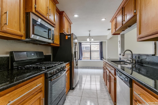 kitchen with sink, dark stone counters, hanging light fixtures, light tile patterned floors, and stainless steel appliances