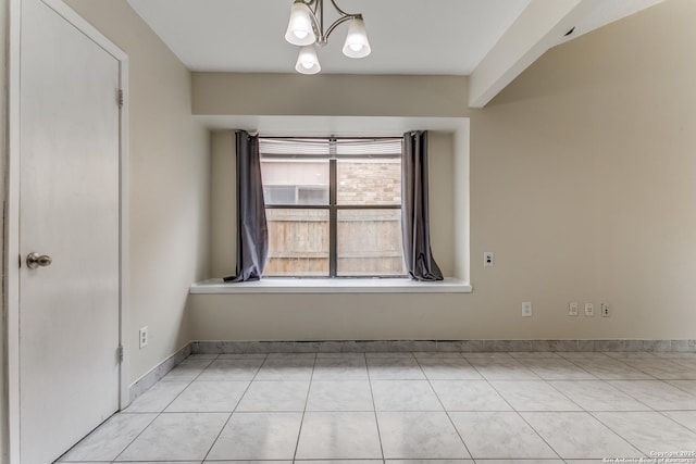 empty room featuring light tile patterned floors and a notable chandelier