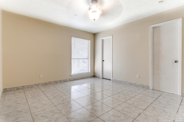 spare room featuring a textured ceiling and light tile patterned floors