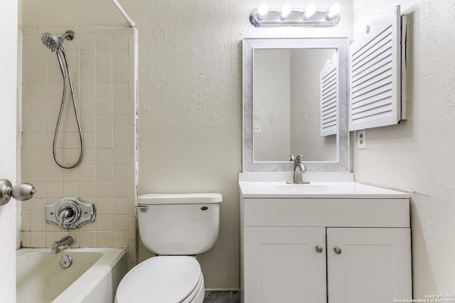 full bathroom featuring tiled shower / bath, vanity, and toilet