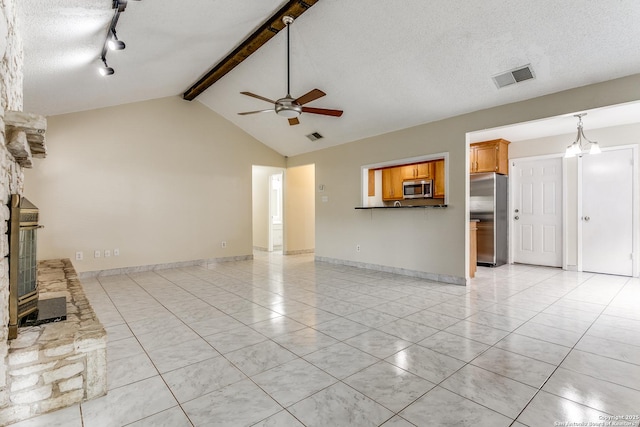 unfurnished living room featuring lofted ceiling with beams, a textured ceiling, light tile patterned floors, track lighting, and ceiling fan