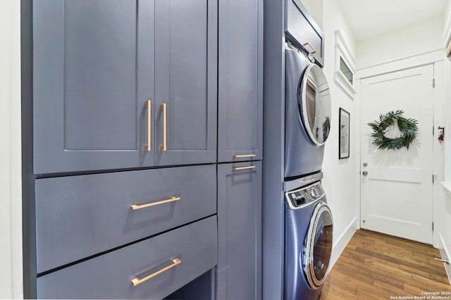 washroom with cabinets, stacked washer and clothes dryer, and dark hardwood / wood-style flooring