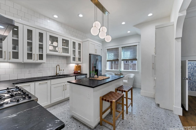 kitchen with sink, a center island, appliances with stainless steel finishes, pendant lighting, and white cabinets