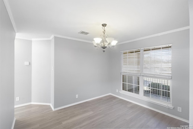 empty room with hardwood / wood-style flooring, crown molding, and a notable chandelier