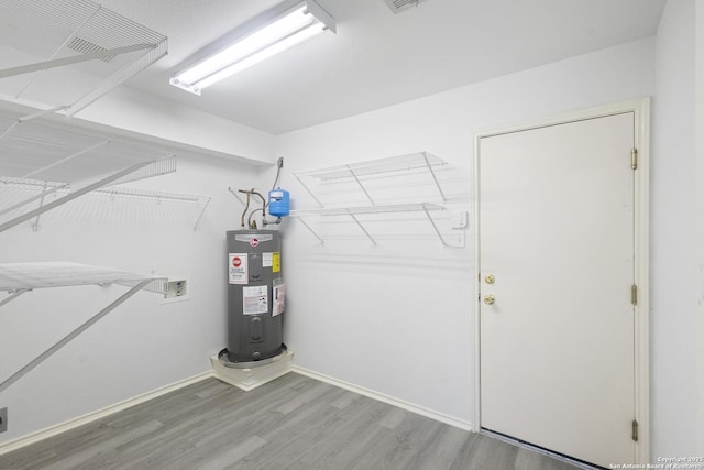 clothes washing area with hardwood / wood-style floors, hookup for a washing machine, and water heater