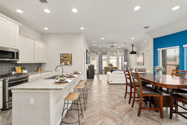 kitchen featuring sink, stainless steel appliances, light stone countertops, light parquet floors, and backsplash