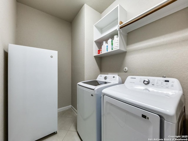 clothes washing area with light tile patterned flooring and separate washer and dryer