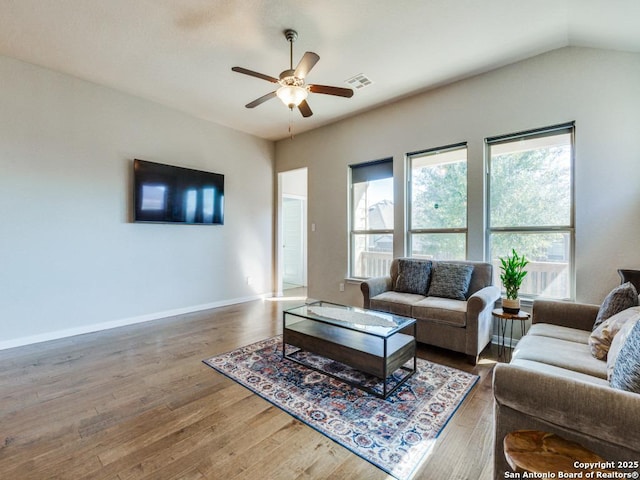 living room with hardwood / wood-style flooring, ceiling fan, and vaulted ceiling