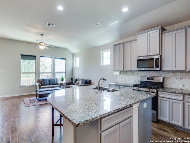 kitchen featuring dark wood-type flooring, stainless steel appliances, a kitchen island with sink, and sink