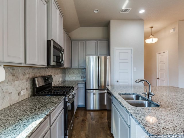 kitchen featuring pendant lighting, sink, dark wood-type flooring, appliances with stainless steel finishes, and light stone countertops