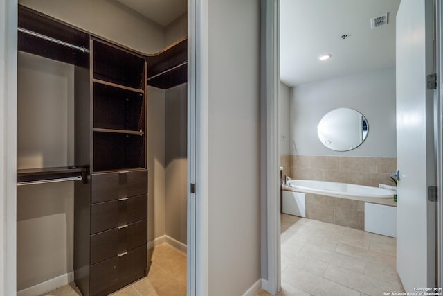 bathroom with tile patterned floors and tiled bath