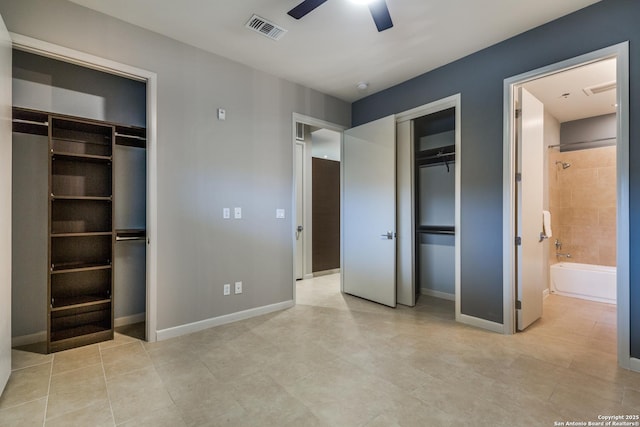 unfurnished bedroom with ceiling fan, ensuite bath, and two closets