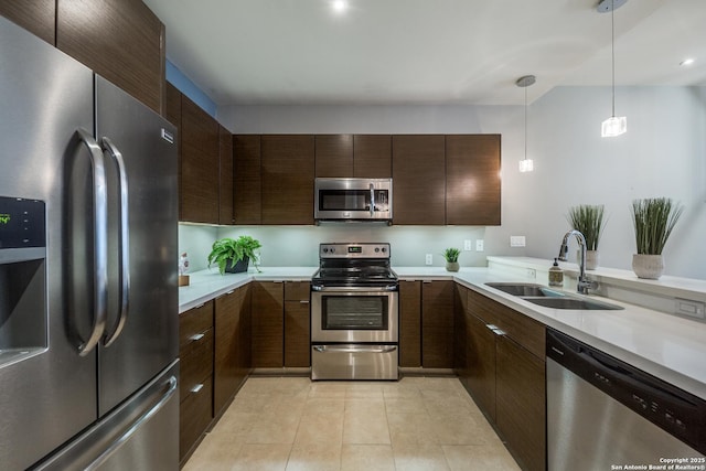 kitchen with appliances with stainless steel finishes, sink, hanging light fixtures, light tile patterned floors, and dark brown cabinetry