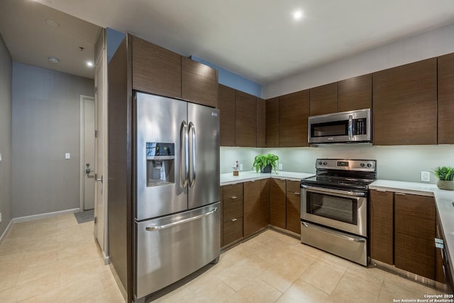 kitchen featuring appliances with stainless steel finishes, light tile patterned floors, and dark brown cabinetry