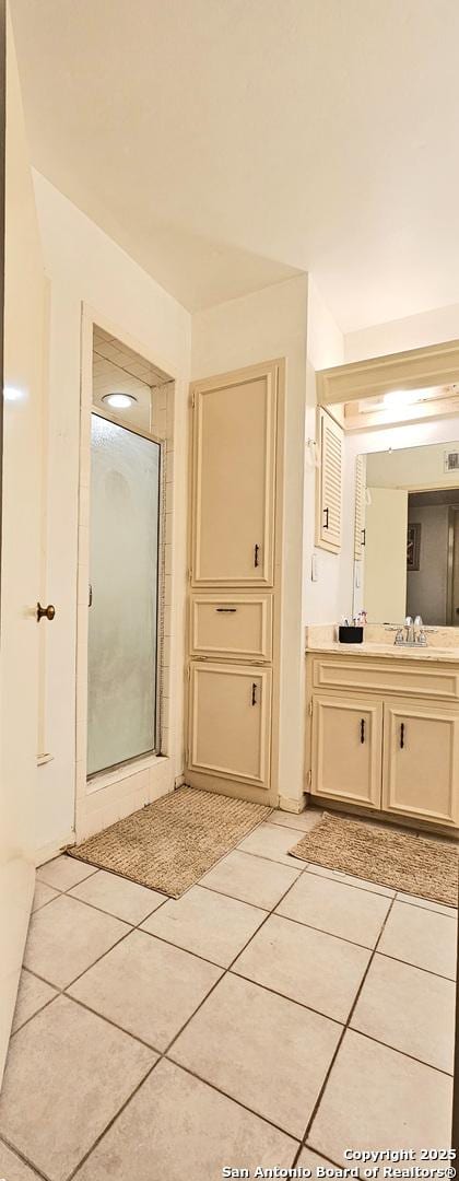 bathroom with tile patterned floors, a shower with shower door, and vanity