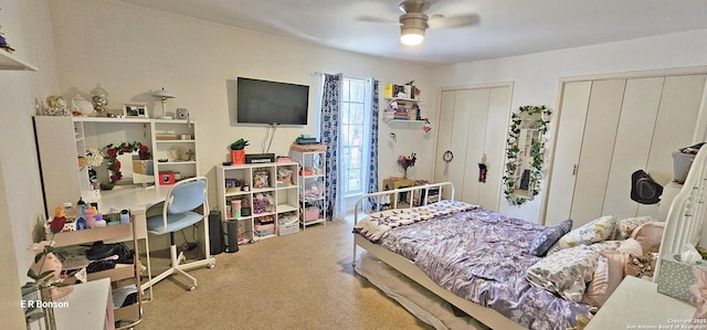 bedroom with light carpet, ceiling fan, and multiple closets