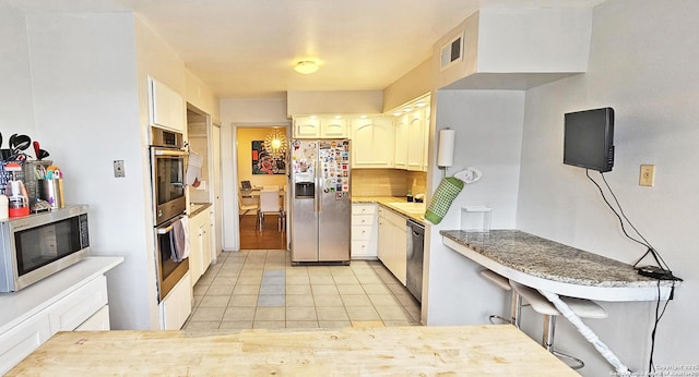 kitchen featuring appliances with stainless steel finishes, light tile patterned floors, and decorative backsplash