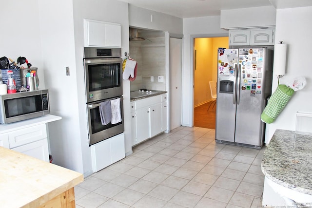 kitchen with light stone counters, light tile patterned floors, white cabinetry, and stainless steel appliances