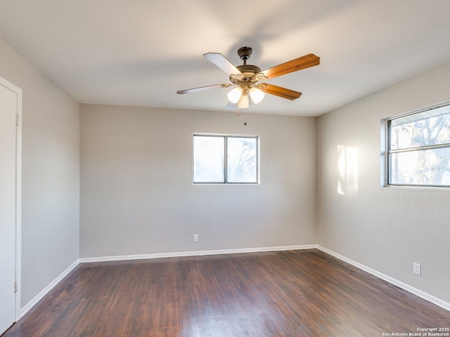 spare room with dark wood-type flooring, plenty of natural light, and ceiling fan