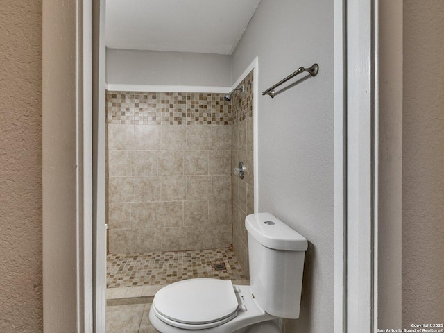 bathroom featuring tiled shower and toilet