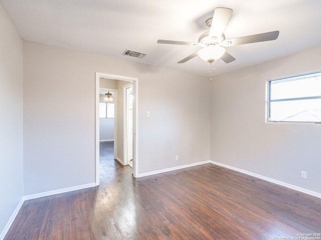 spare room featuring ceiling fan, a healthy amount of sunlight, and dark hardwood / wood-style floors