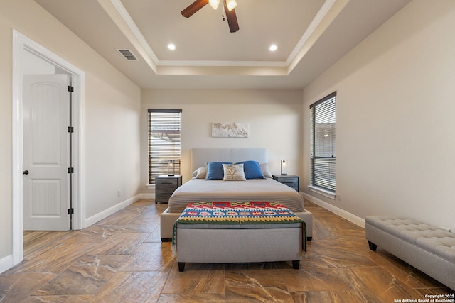 bedroom featuring ceiling fan, ornamental molding, a tray ceiling, and multiple windows