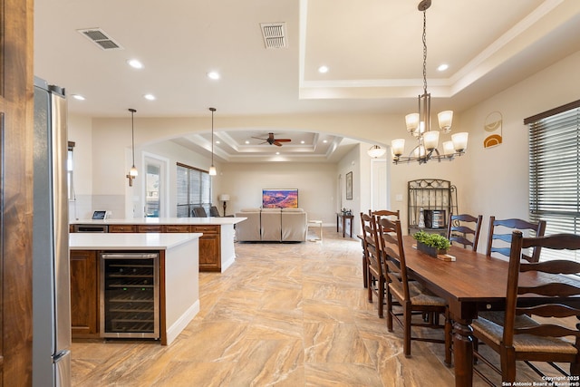 dining area with a healthy amount of sunlight, ceiling fan, a tray ceiling, and beverage cooler