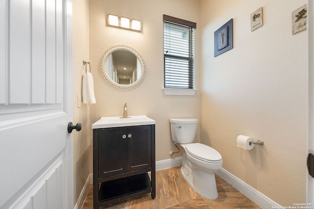 bathroom featuring wood-type flooring, toilet, and vanity