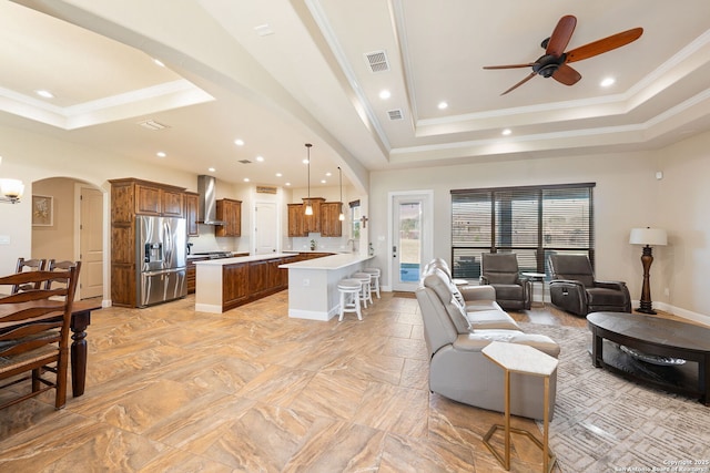 living room featuring ceiling fan, ornamental molding, and a tray ceiling