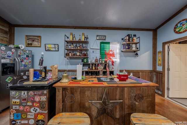 bar with crown molding, wooden walls, and stainless steel fridge