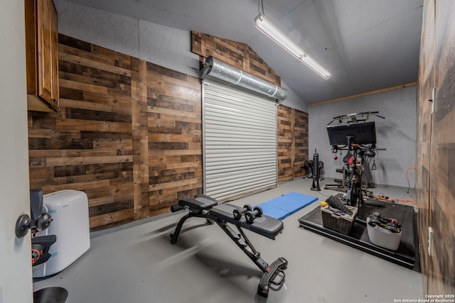 workout area featuring vaulted ceiling and wood walls