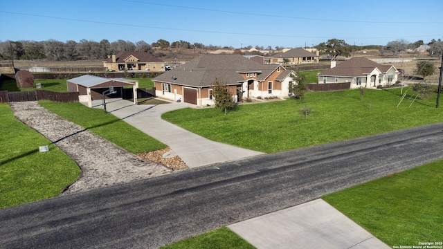 view of front facade with a front lawn, a residential view, a carport, concrete driveway, and fence