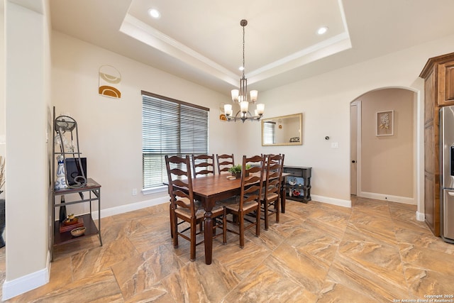 dining space with a raised ceiling, ornamental molding, and a notable chandelier