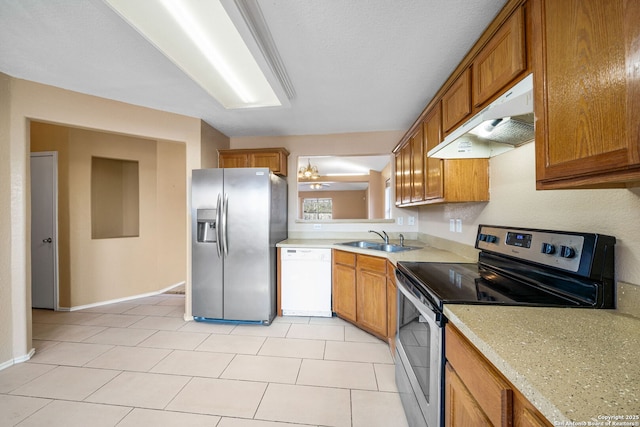 kitchen featuring stainless steel appliances, sink, light tile patterned floors, and light stone counters