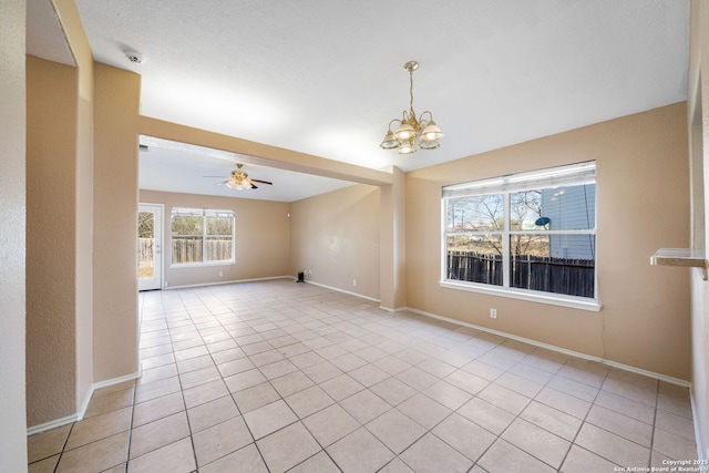 tiled spare room with ceiling fan with notable chandelier