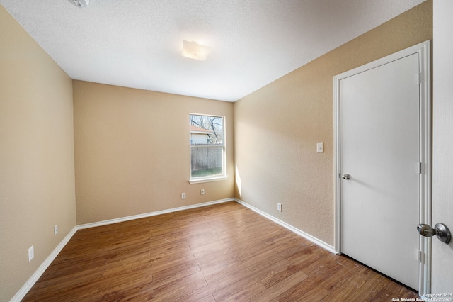 unfurnished room featuring hardwood / wood-style flooring and a textured ceiling