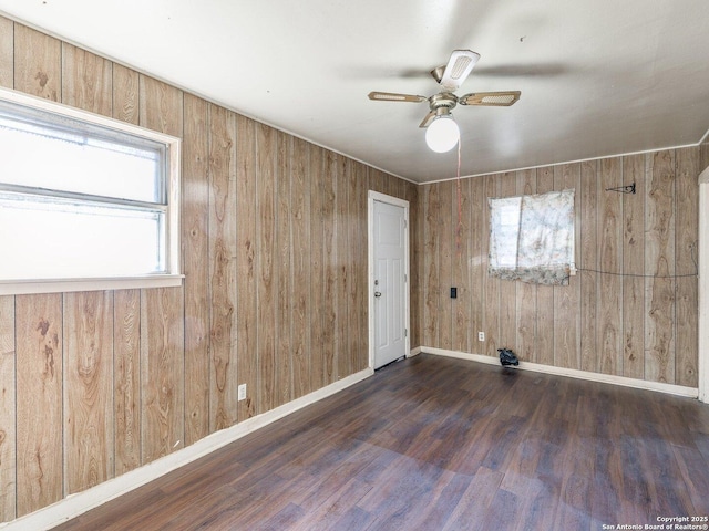 spare room featuring dark hardwood / wood-style floors, ceiling fan, and wood walls