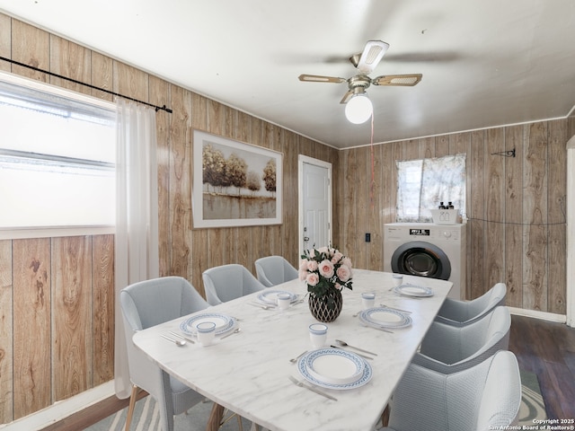 dining space featuring washer / clothes dryer, dark wood-type flooring, ceiling fan, and wood walls